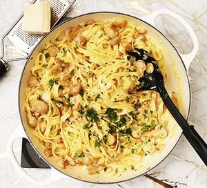 a skillet filled with pasta, mushrooms and parmesan cheese on a marble table