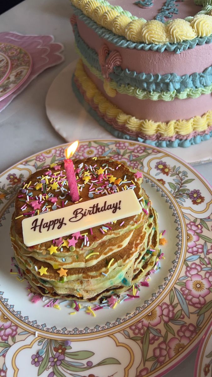 a birthday cake with a lit candle on top of it sitting on a decorated plate