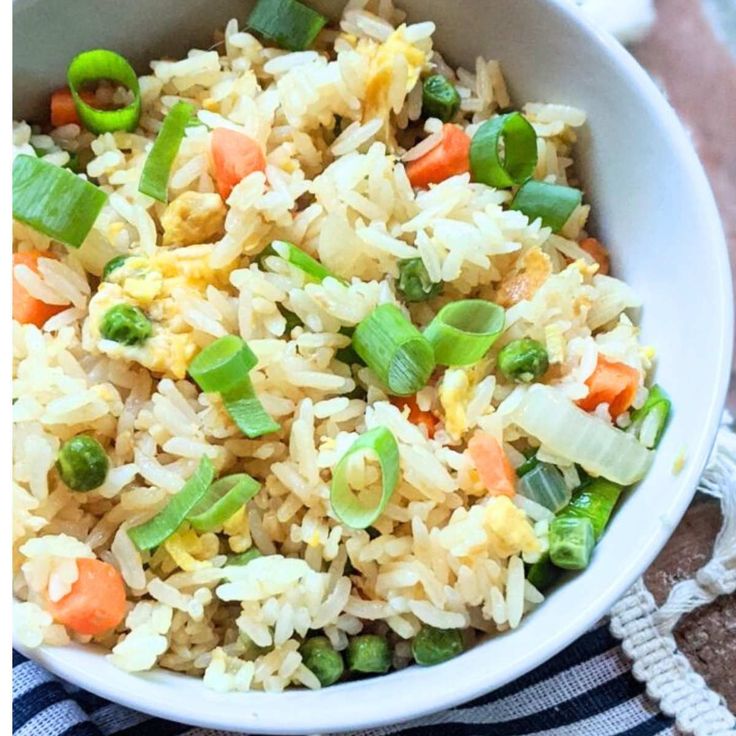 a white bowl filled with rice and veggies on top of a blue and white towel