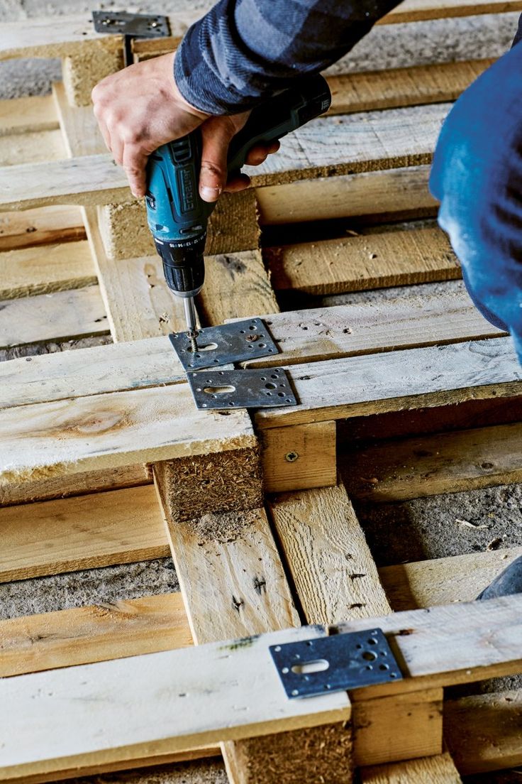 a person using a drill to attach wood planks