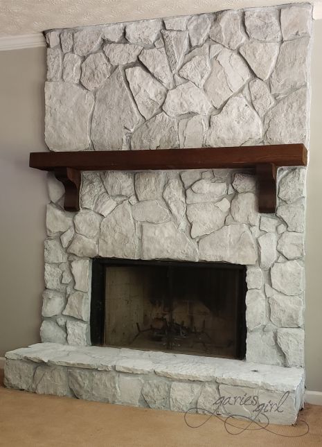 a stone fireplace in a living room next to a wall