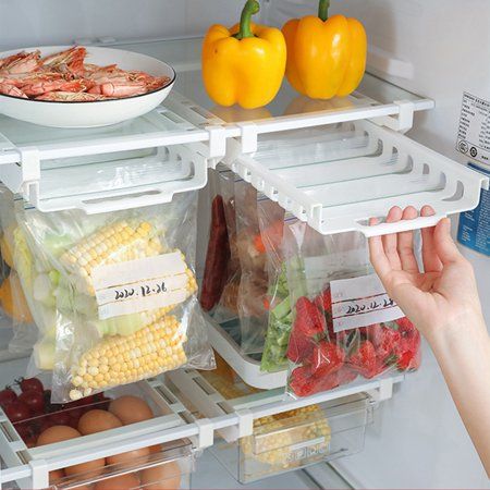 the refrigerator door is open to show fresh food and vegetables in plastic bags on shelves