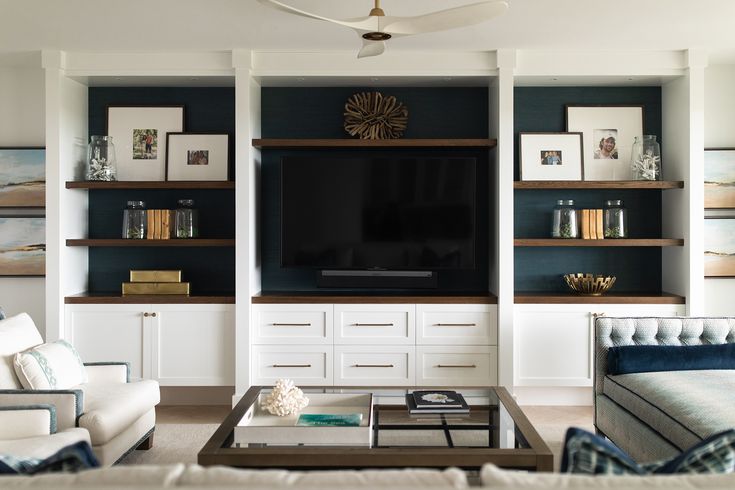 a living room filled with furniture and a flat screen tv mounted on a wall above a coffee table