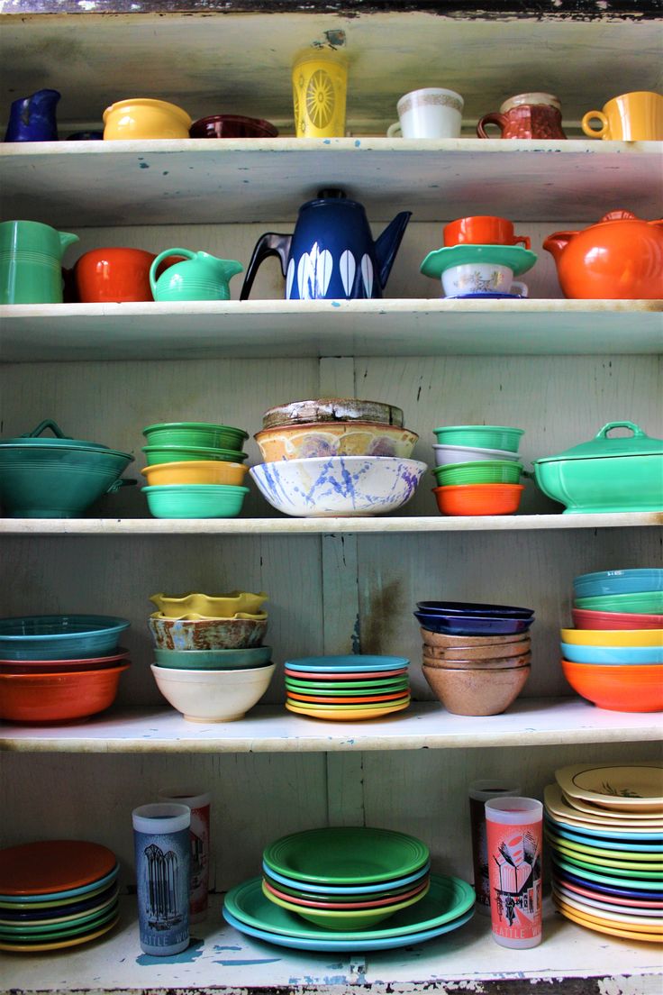 the shelves are filled with colorful dishes and bowls