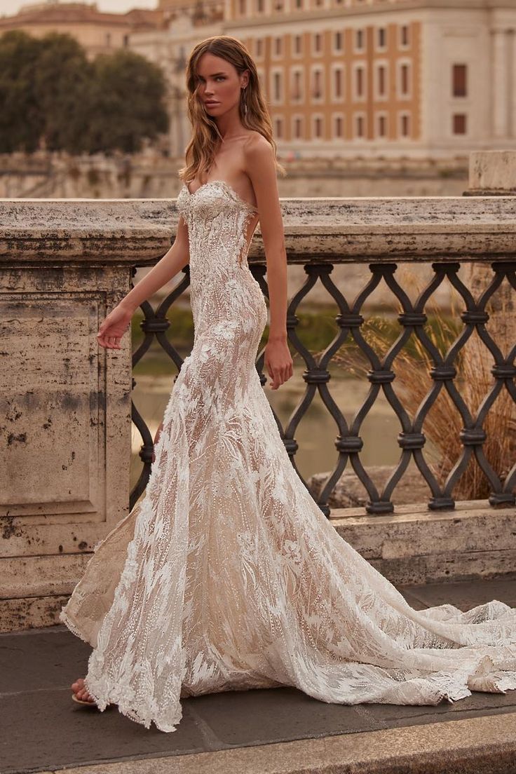 a woman in a white wedding dress standing on a bridge with buildings in the background