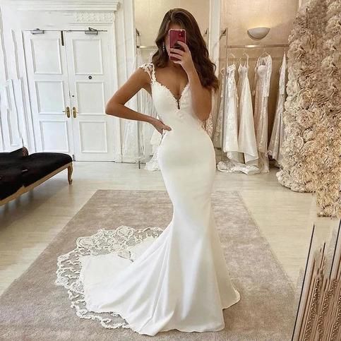 a woman taking a selfie in front of a mirror wearing a white wedding dress