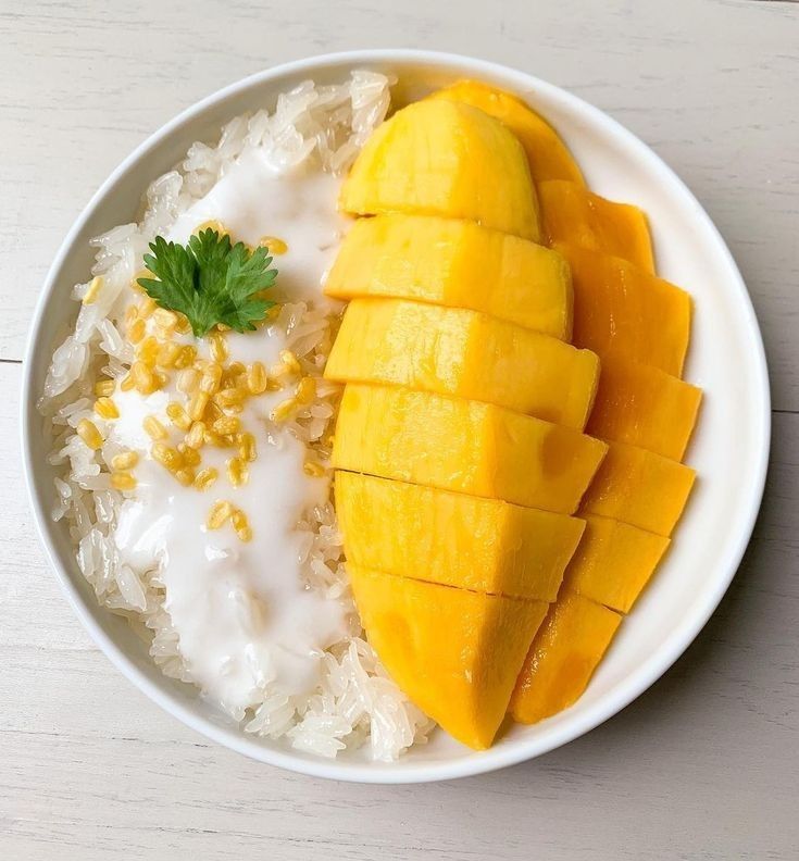 a white plate topped with rice and mango slices