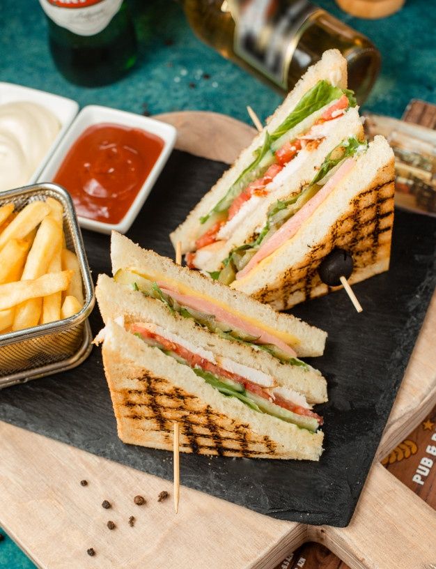 a sandwich cut in half sitting on top of a cutting board next to french fries and ketchup