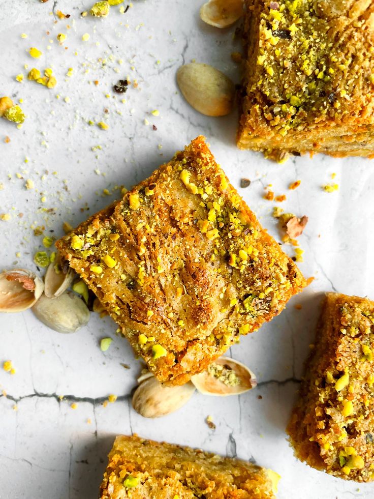 several pieces of bread with nuts and pistachios on the top one is cut in half