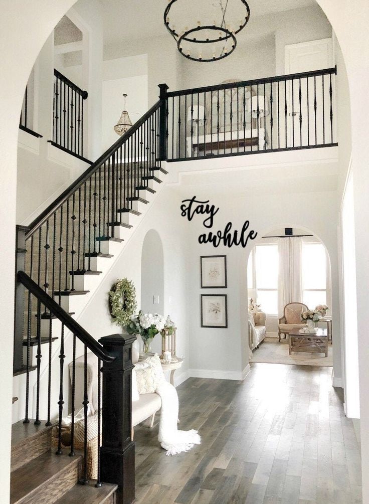 a staircase in a house with white walls and wood floors, chandelier above the stairs