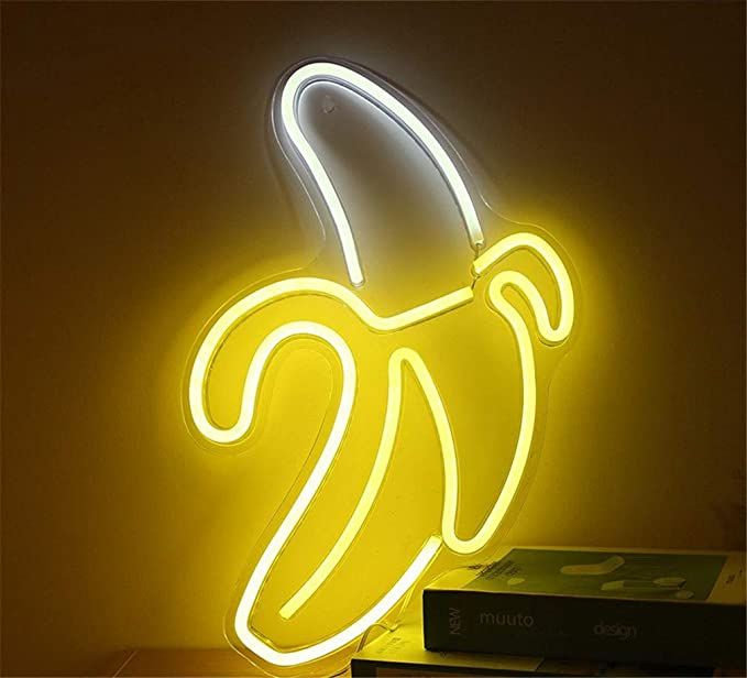 a neon banana sign sitting on top of a wooden table next to a stack of books