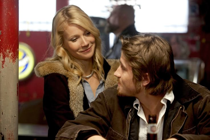 a man sitting next to a woman at a table in front of a red pole