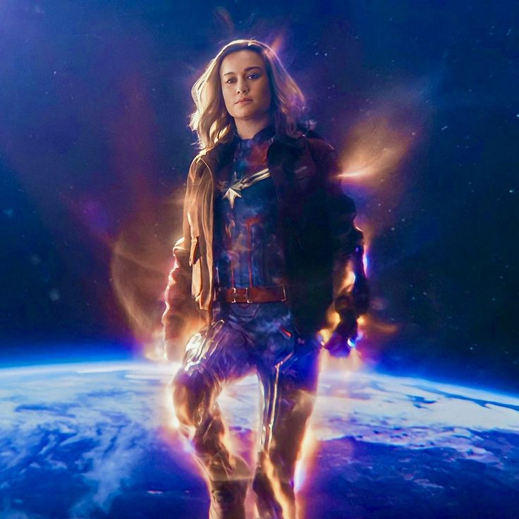 a woman standing in front of the earth with fire coming out of her pants and jacket