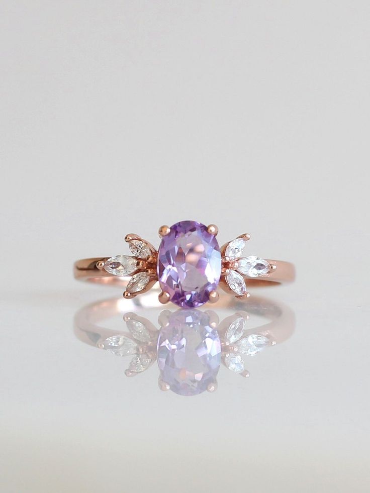 The immaculate vibes of our Contessa Ring are absolutely unmatched. ✨ The pristine and opulent amethyst crystal is framed by two delicate cubic zirconia blossoms in this delicate design. Delicate and regal, unique yet versatile, the Contessa Ring is a unique and stunning addition to any jewelry collection. 💜 Complete the look with our Tiara Stacker, Arc Stacker or Sweetheart Stacker! * * * Don't know your ring size? View our Ring Size Guide * * * …………………………………. RING SIZE & MATERIAL❋ 18k rose go Dainty Amethyst Wedding Ring, Delicate Amethyst Anniversary Ring, Delicate Amethyst Ring For Anniversary, Dainty Lavender Amethyst Ring, Dainty Rose Gold Amethyst Wedding Ring, Dainty Amethyst Ring In Lavender, Dainty Amethyst Wedding Ring With Prong Setting, Classic Lavender Jewelry For Wedding, Dainty Purple Wedding Ring