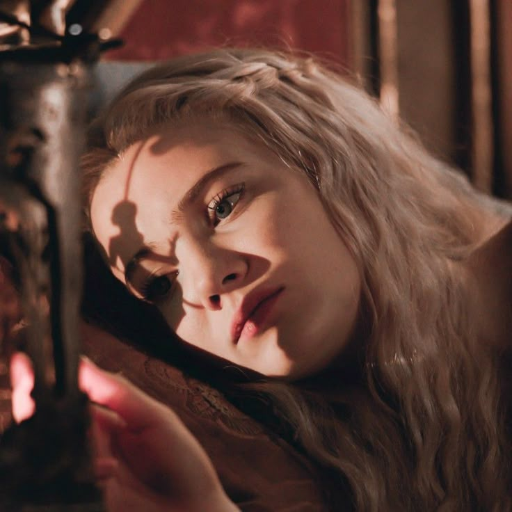 a woman with long blonde hair is looking at something in her hand while holding a clock