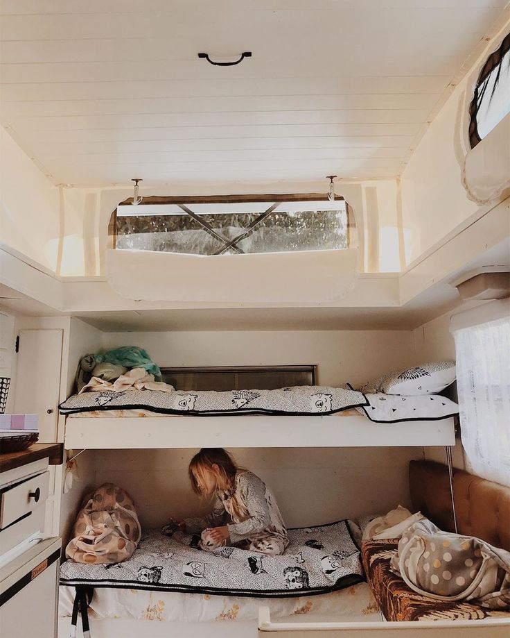 a woman sitting on top of bunk beds in a room with white walls and floors