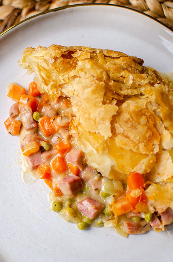 a white plate topped with food on top of a woven place mat next to a fork and knife