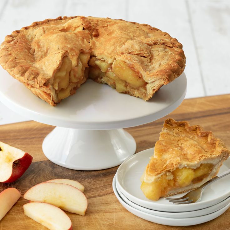 an apple pie on a cake stand with slices cut out and ready to be eaten