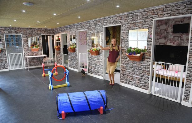 a woman standing next to a child in a room with play equipment on the floor