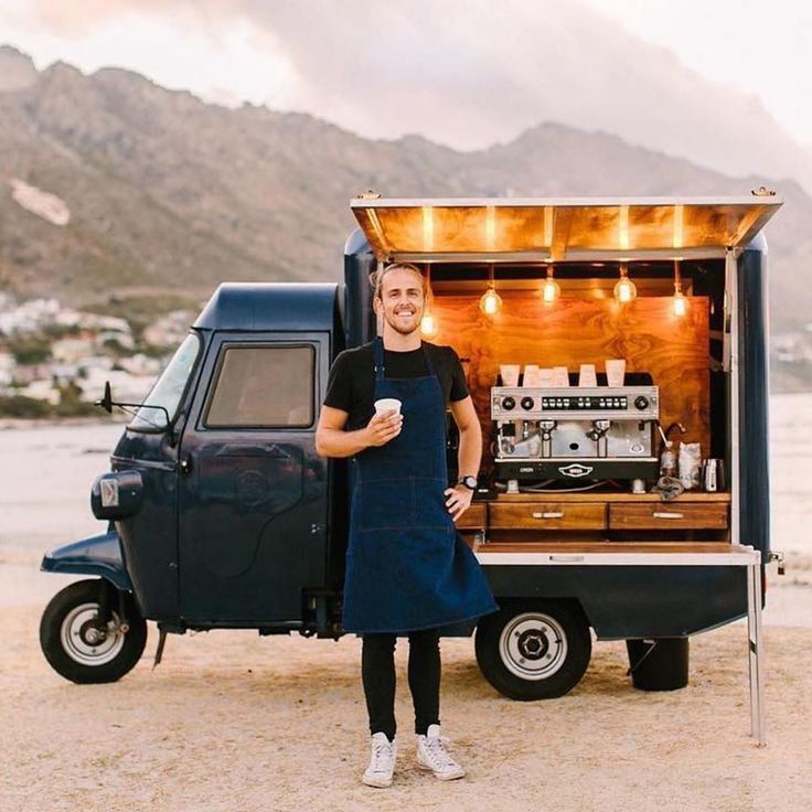 a man standing in front of a truck with an open door and coffee machine on the back