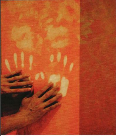 two hands touching each other in front of an orange and red wall with candles on it