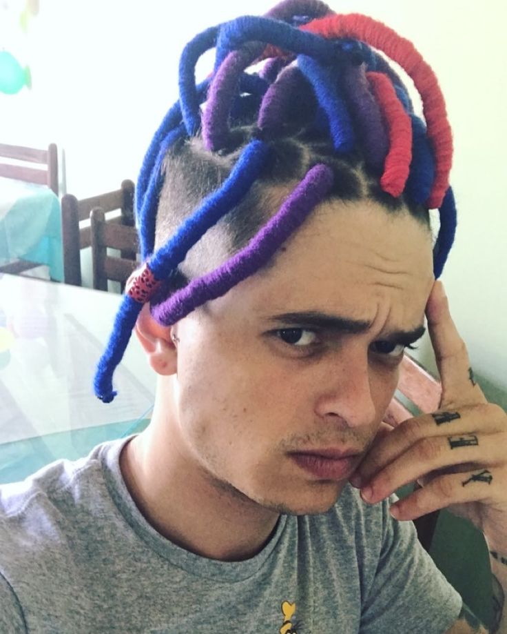 a young man with dreadlocks on his head talking on the phone while sitting at a table