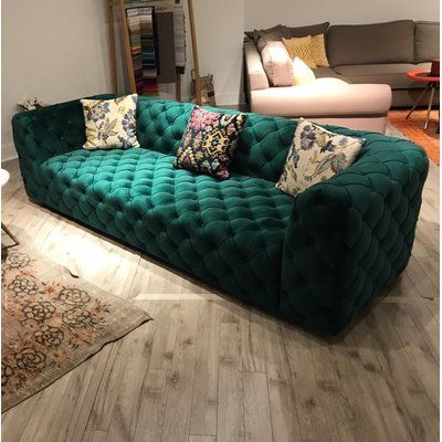 a large green couch sitting on top of a wooden floor next to a chair and rug