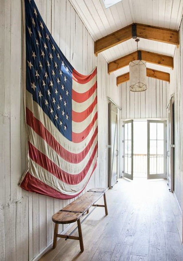 an american flag hanging on the wall next to a bench in a room with white walls