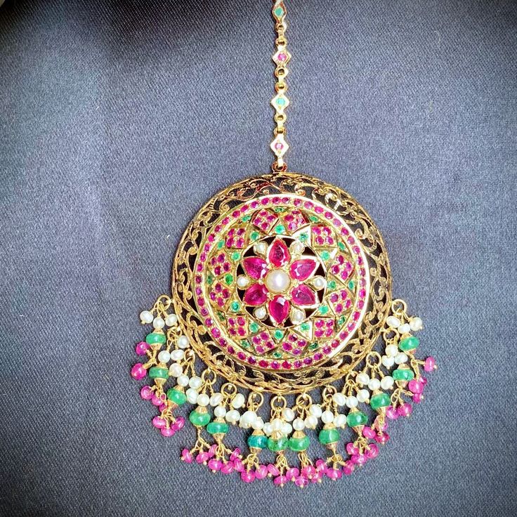 Featured is an oversized 22k gold jadau bridal mang teeka. The teeka includes the chain and weighs 23.8gms including 3.95gms in the hanging ruby emerald and pearl beads. Festive Yellow Gold Tikka With Tilla, Festive Yellow Gold Tilla Tikka, Yellow Gold Tikka For Festivals, Festive Yellow Gold Tikka For Festivals, Ceremonial Gold Chandbali Tikka, Celebration Temple Jewelry Tikka With Hand Set, Yellow Gold Kundan Necklace With Latkans For Celebration, Yellow Gold Kundan Necklace With Latkans For Festive Occasions, Festive Yellow Gold Kundan Necklace With Latkans