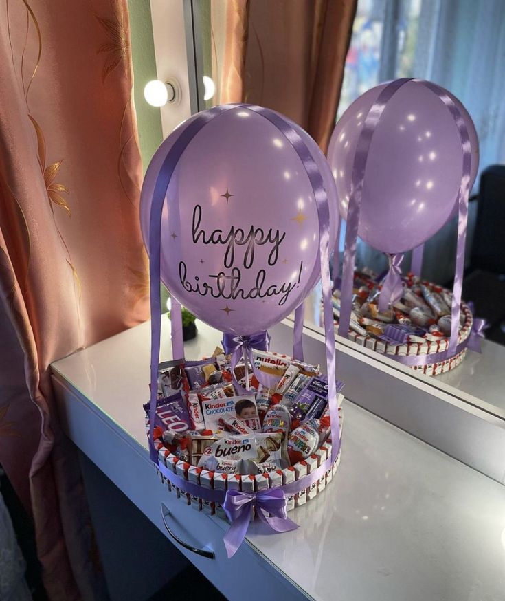 a birthday basket with balloons and candies for someone's special occasion on the table