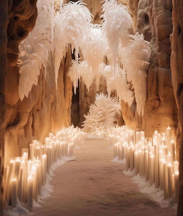 an indoor area with candles and white feathers hanging from the ceiling, surrounded by stone walls