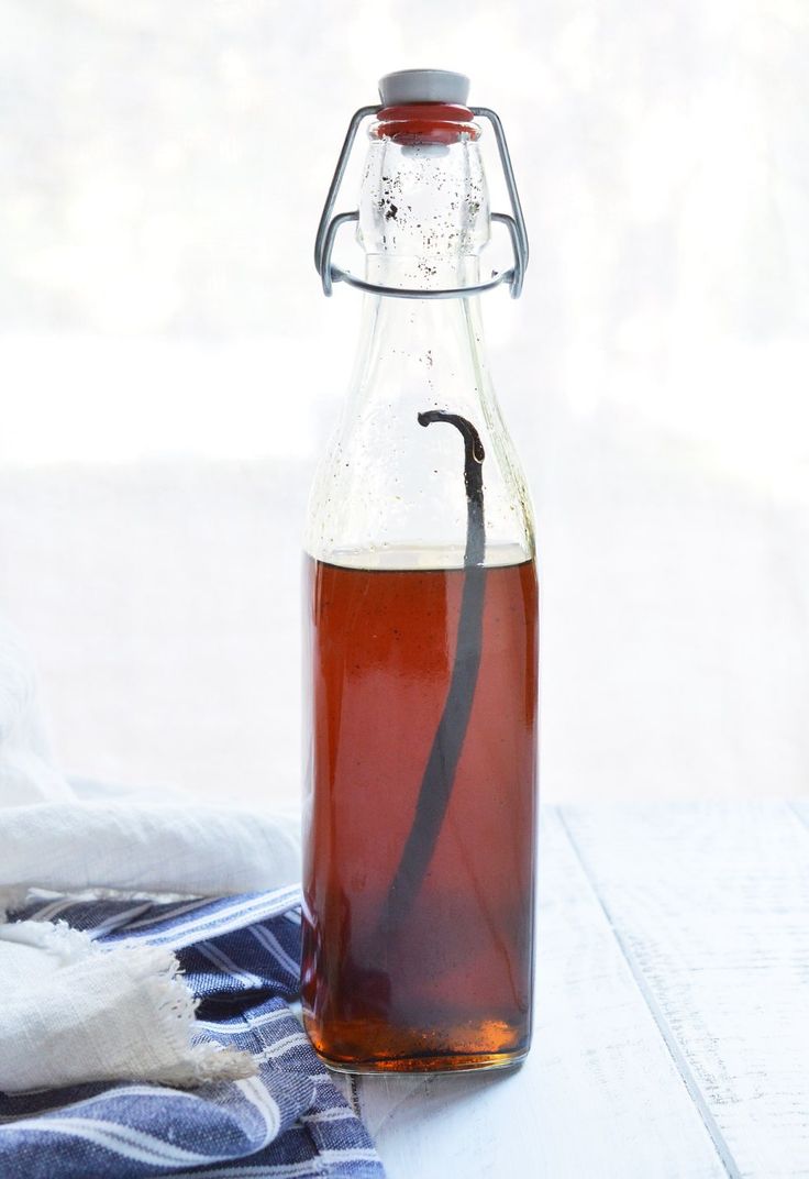 a glass bottle filled with liquid sitting on top of a blue and white table cloth