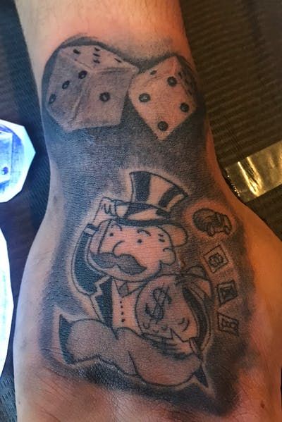 a man's hand with dices on it and a dog wearing a top hat