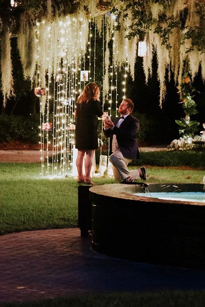 a man and woman standing in front of a fountain with lights hanging from the ceiling