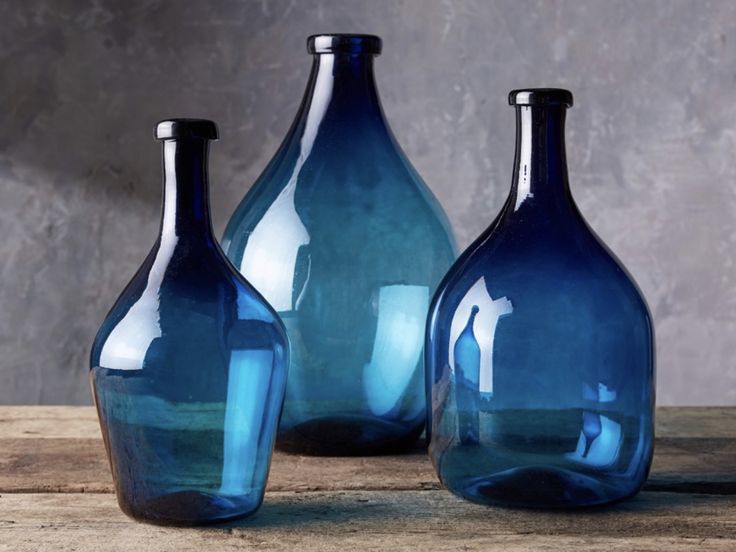 three blue glass vases sitting on top of a wooden table next to each other