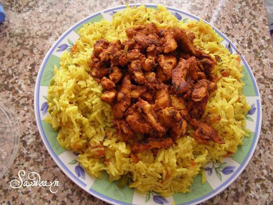 a plate full of rice and meat on top of a granite counter with water bottles in the background