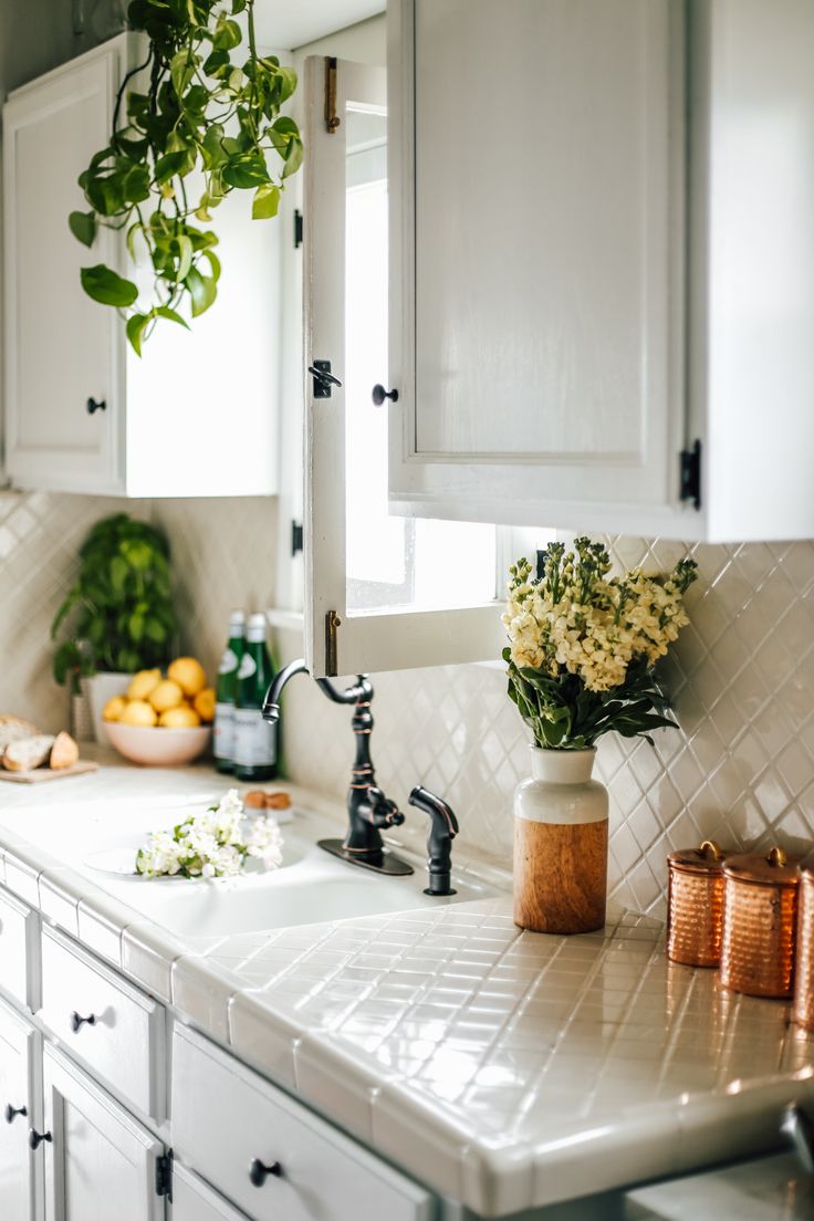 a kitchen with white cabinets and flowers on the counter