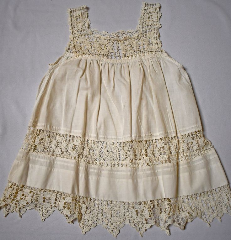 A beautiful antique Victorian or Edwardian soft white cotton loose shift dress or petticoat with wide hand made crocheted bodice, and inset trim in the skirt and hem.  The dress has a square neckline, there are is a back snap placket.  There are gathers under the lace yoke, an inset row of 2 3/4 inch lace at the lower skirt and the hem is trimmed with 4 inch wide pointed-edge lace.  There are two small repairs (3/8 inch and 1/8 inch within the gathers at the chest and 1/4 inch pale brown dot on the left center front.  No other stains, rips or holes.  Please check the measurements of the dress against your child's measurements, as I have to guess at sizing.  30 inches around the chest, 25 inches in length from the shoulder to the hem.  6 oz. Please also follow me on Instagram at ChrisMartin Vintage Cream Crochet Top With Trim, Vintage Cream Crochet Top With Crochet Trim, Vintage Cream Lace Crochet Top, Vintage Crochet Top With Lace Trim For Summer, Vintage Beige Crochet Top With Crochet Trim, Bohemian Cotton Crochet Dress With Lace Trim, Bohemian Crochet Cotton Dress With Lace Trim, Vintage Cotton Crochet Trim Top, Spring Vintage Crochet Top With Lace Work