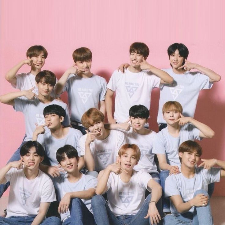 a group of young men sitting next to each other in front of a pink wall