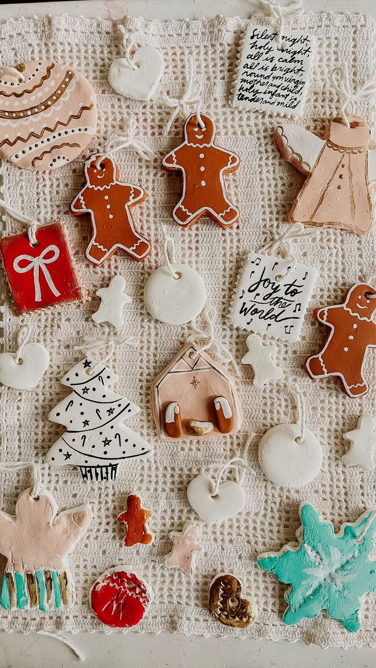 many different decorated cookies on a white table cloth with writing and ornaments around them,