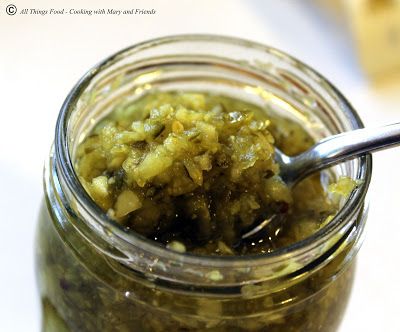 a jar filled with pickled vegetables on top of a table next to a spoon