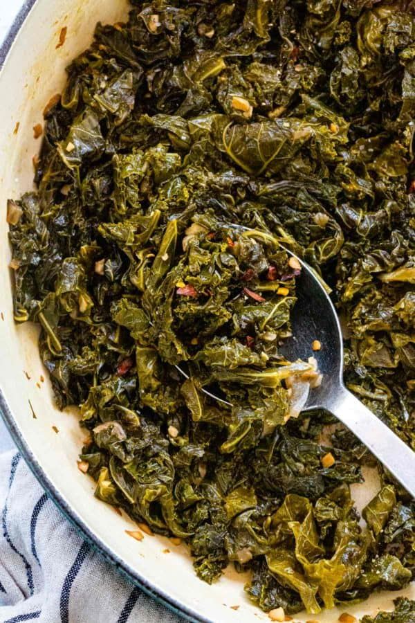 a bowl filled with cooked collard greens and a spoon