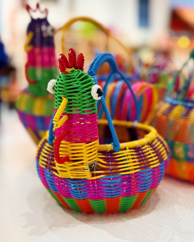 colorful woven baskets are sitting on the table, with one chicken in it's basket