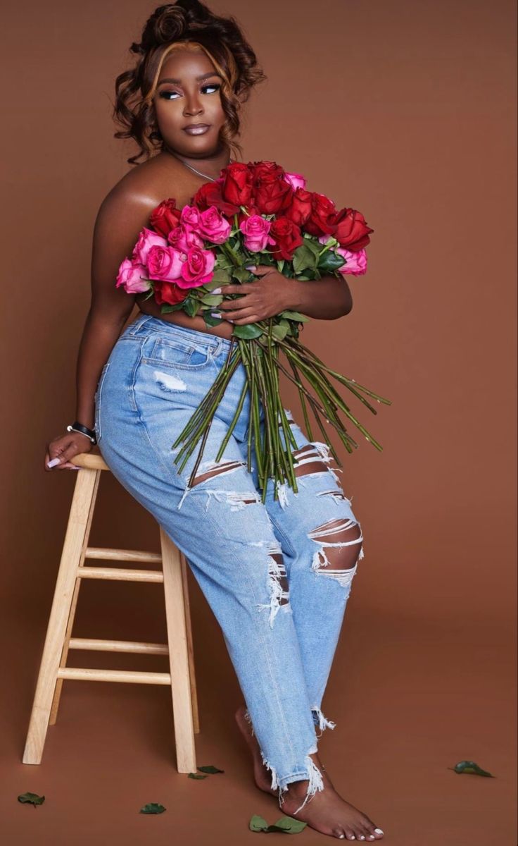 a woman sitting on a stool with flowers in her lap and one leg bent up