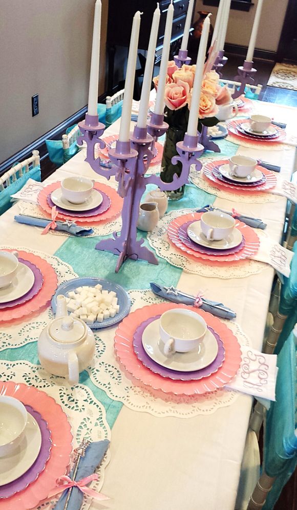 the table is set with tea cups, plates and napkins for two people to sit at