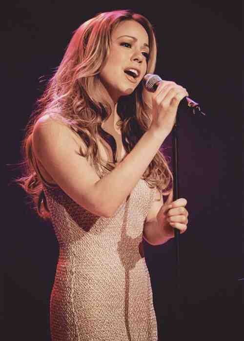 a woman in a white dress holding a microphone and singing into a mic on stage