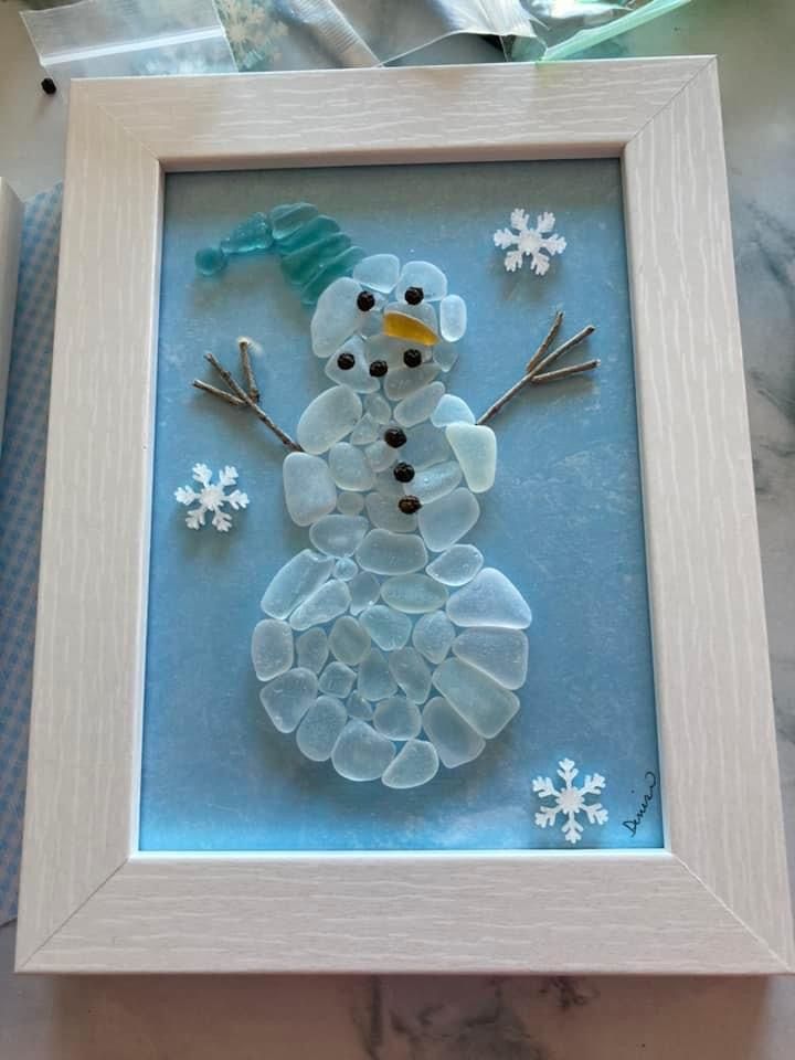 a snowman made out of sea glass in a frame