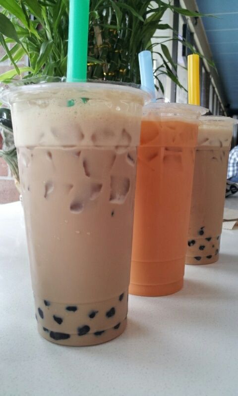 three drinks sitting on top of a table next to each other in front of a plant