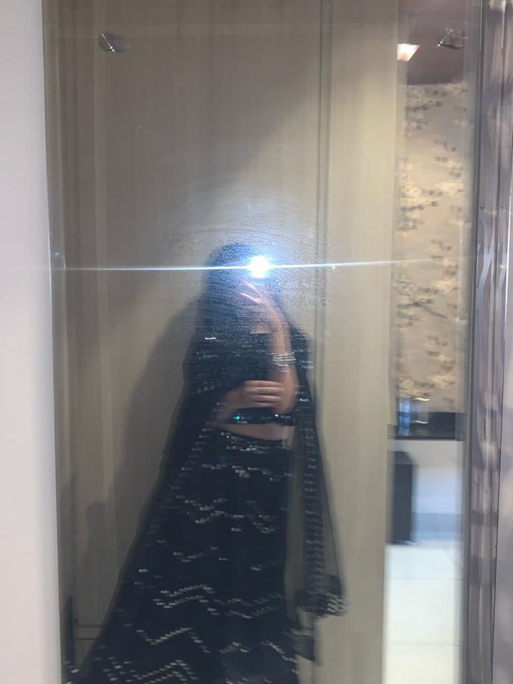 a woman taking a selfie in front of a mirror while wearing a black dress