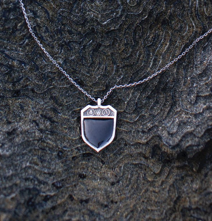 Ambrosio's Shield Pendant– a majestic emblem inspired by the timeless significance of signet rings. Adorned with intricate details, this pendant exudes strength and nobility. At its heart lies a striking Black Onyx stone, elegantly placed within the center of the shield. Crafted from high-quality Sterling Silver 925, this pendant is a symbol of resilience and sophistication, making it a distinguished addition to any jewelry collection. Sterling Silver 925 Shield pendant, inspired by the signet r Luxury Silver Necklace With Black Enamel, Formal White Gold Amulet Jewelry, Oval White Gold Jewelry With Black Enamel, Classic Intaglio Medallion Jewelry, Classic Medallion Intaglio Jewelry, Timeless Intaglio Jewelry For Anniversary, Black Enamel Sterling Silver Fine Jewelry, Sterling Silver Fine Jewelry With Black Enamel, Luxury Sterling Silver Jewelry With Black Enamel